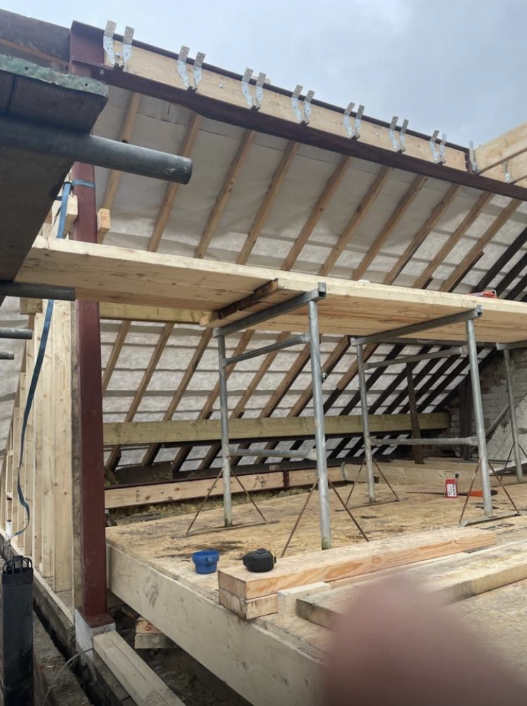 Red steel beams supporting a roof extension with timber rafters