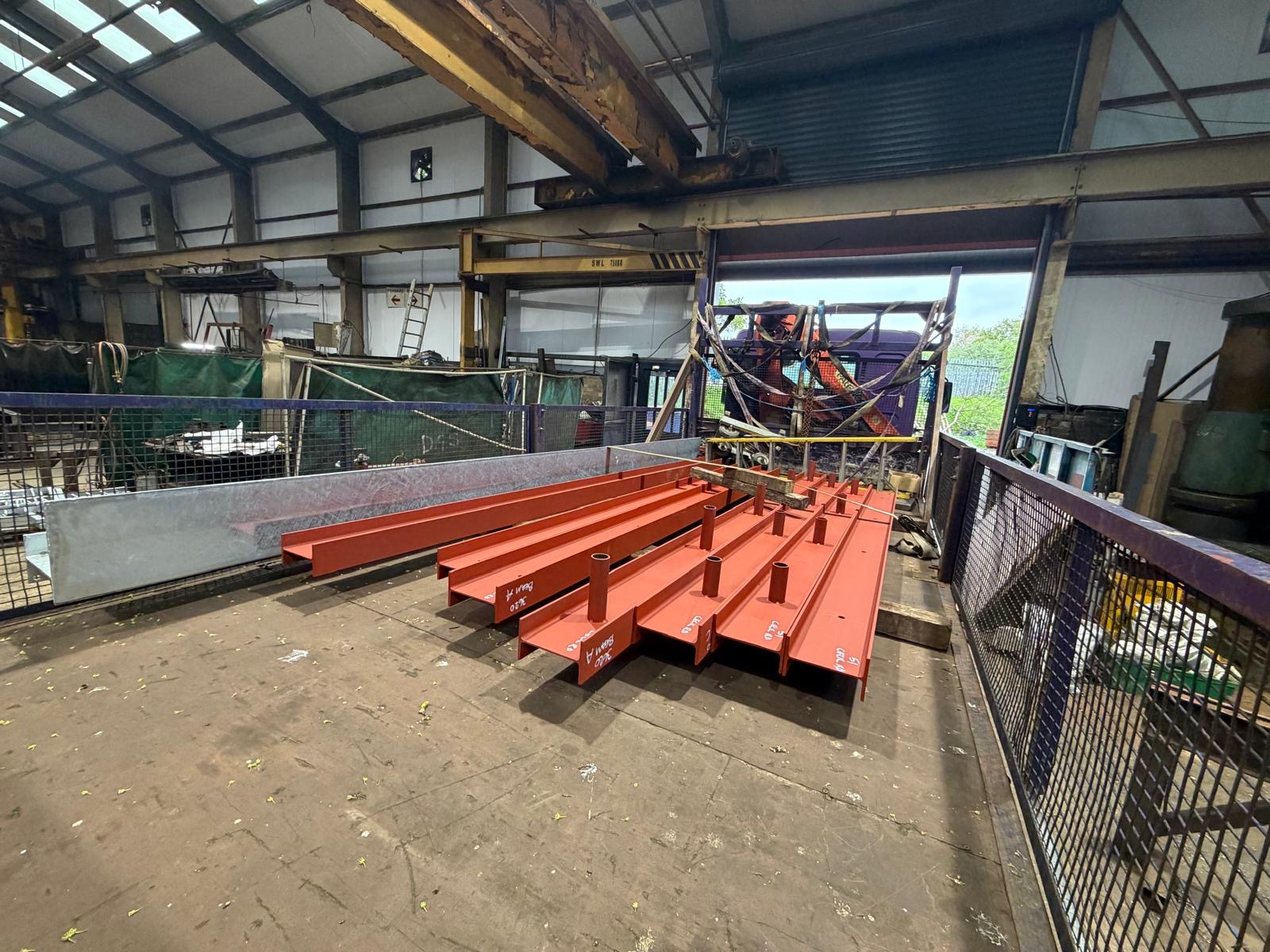 Labelled red fabricated beams in the workshop bay